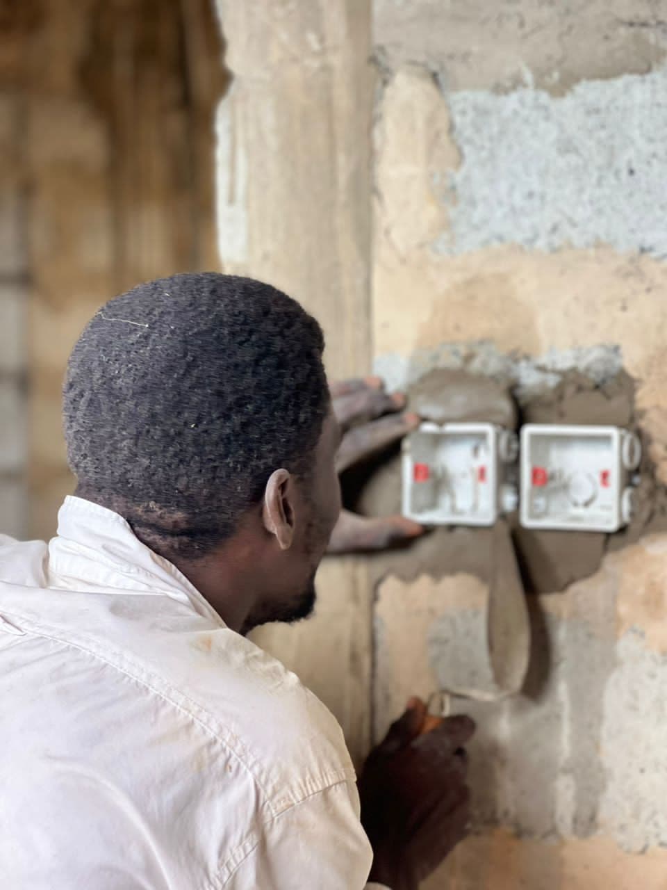Electrician plastering around a newly installed double socket outlet box
