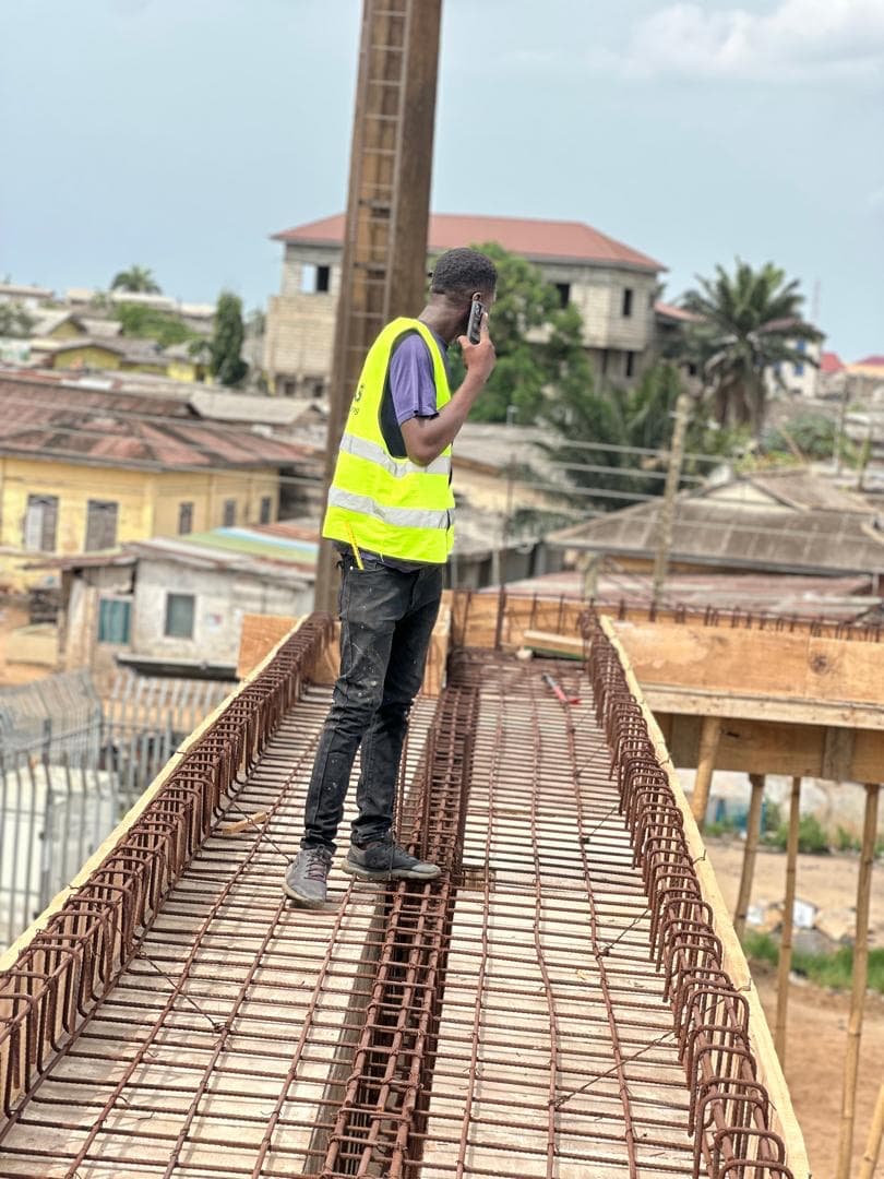 Site supervisor on a rooftop slab coordinating work by phone
